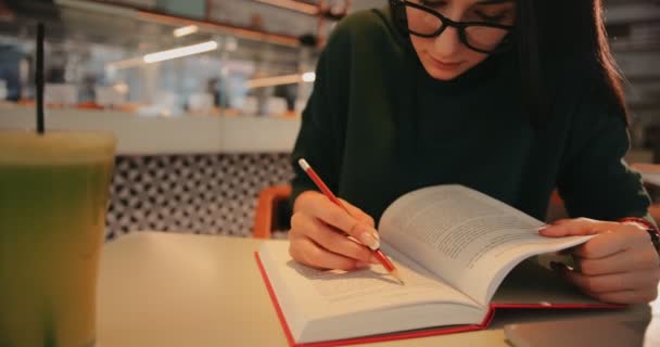 Ung kvinna med bok under och studerar på urban café — Stockvideo