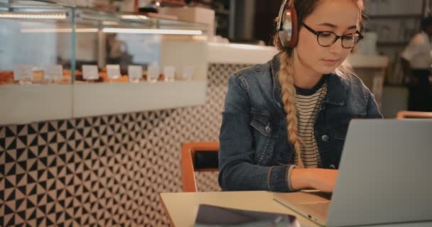 Студентка використовує ноутбук і робить домашнє завдання в кав'ярні — стокове відео
