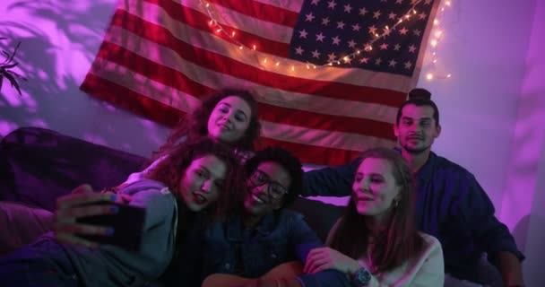 Mladí multietničtí přátelé relaxovat na koleji a brát selfie