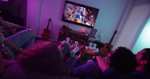 Wieloetniczni przyjaciele oglądają teledyski w telewizji i śpiewają — Wideo stockowe