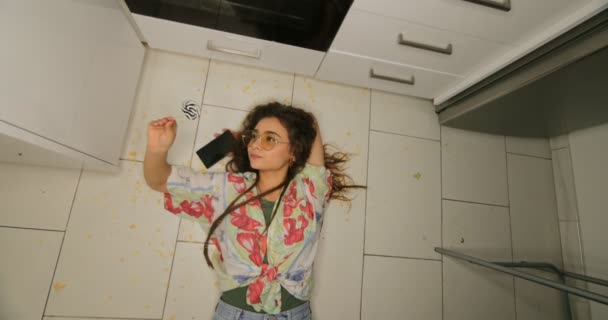 Cool jonge vrouw met lolly liggend op rommelige vloer — Stockvideo