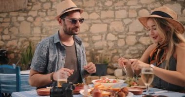 Genç turistler geleneksel Yunan restoranında yemek yerken eğleniyorlar