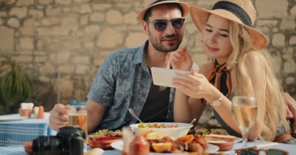 Unga turister avkopplande på Medelhavet restaurang och titta på smartphone — Stockvideo