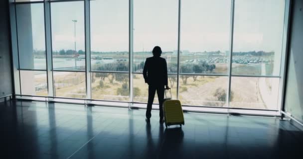 Jonge zakenman in pak kijkt uit op internationale luchthaven raam — Stockvideo