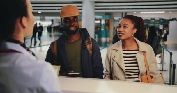 Pareja joven con tarjetas de embarque en el mostrador de facturación del aeropuerto — Vídeo de stock