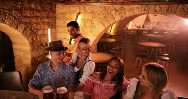 Jóvenes amigos multiétnicos celebrando el Oktoberfest en la fiesta del bar bávaro — Vídeos de Stock