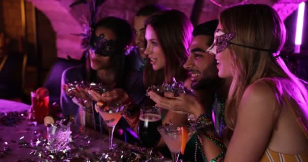 Vrienden vieren Mardi Gras en blazen confetti in nachtclub — Stockvideo