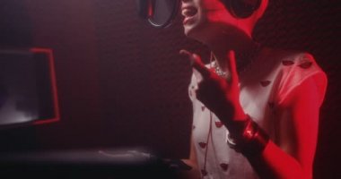Genç bayan pop müzik sanatçısı müzik stüdyosunda şarkı söylüyor.