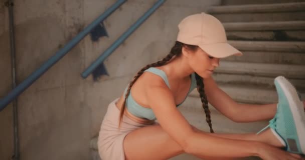 Jeune femme sportive qui s'étire sur un escalier urbain avant de faire du jogging — Video