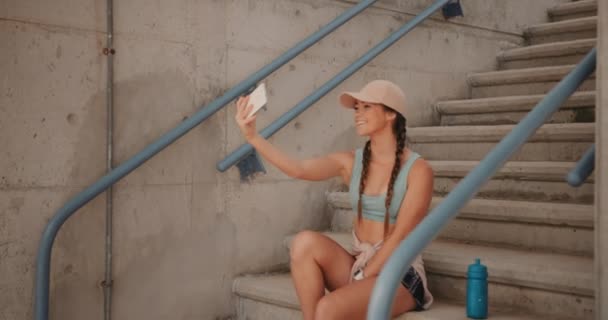 Joven mujer deportiva con smartphone tomando selfies durante el descanso de entrenamiento — Vídeos de Stock