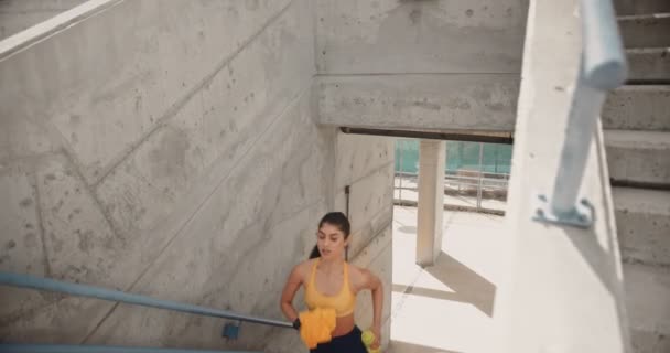 Genç bayan sporcu spor yapıyor ve şehir stadyumunun merdivenlerinde koşuyor. — Stok video