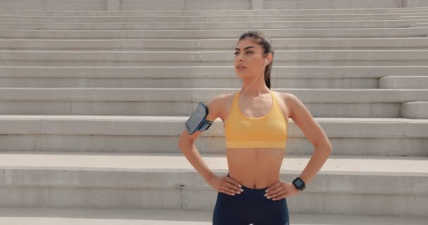 Giovane atleta donna con smartwatch e smartphone che ascolta musica — Video Stock