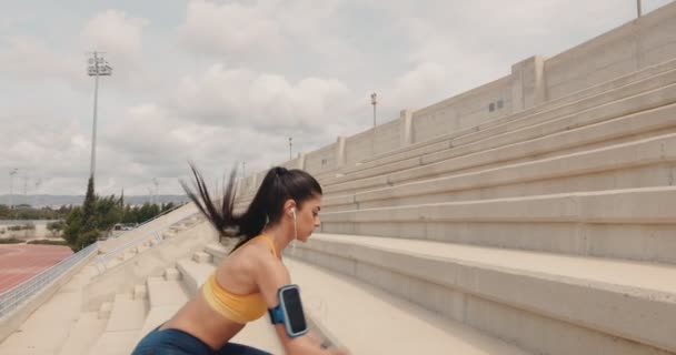 Jeune femme en forme faisant des squats de saut sur les stands de stade urbain — Video