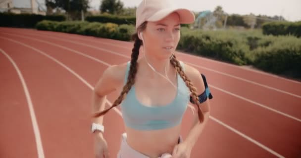 Jeune femme en forme écouter de la musique et courir sur la piste — Video