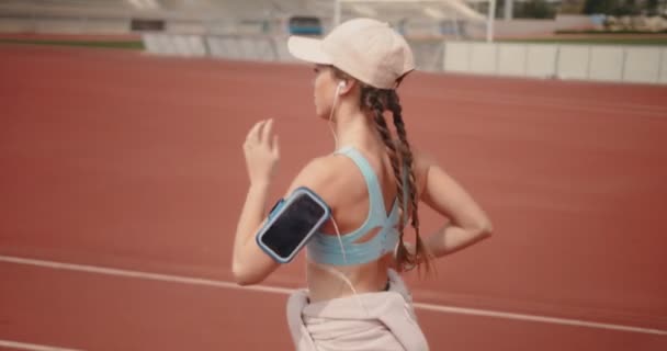 Femme active courant sur piste de sport et écoutant de la musique — Video