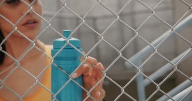 Spor yaptıktan sonra elinde su şişesi olan genç atletik kadın dinleniyor.