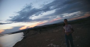 Genç kadın deniz uçurumunda koşuyor ve beşlik çakıyor.
