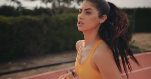 Jovem com treinamento smartwatch correndo em pista de esportes — Vídeo de Stock