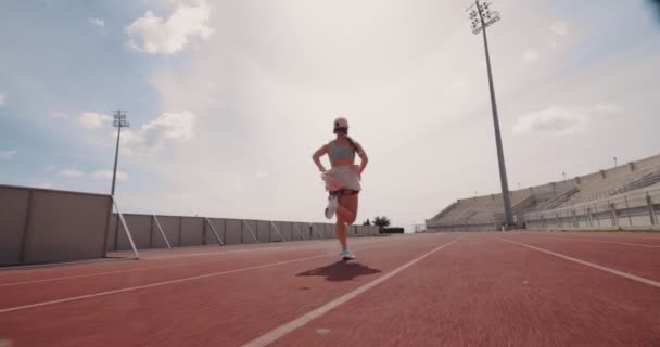 Jeune femme athlétique courir et faire de l'entraînement sur piste de sport — Video