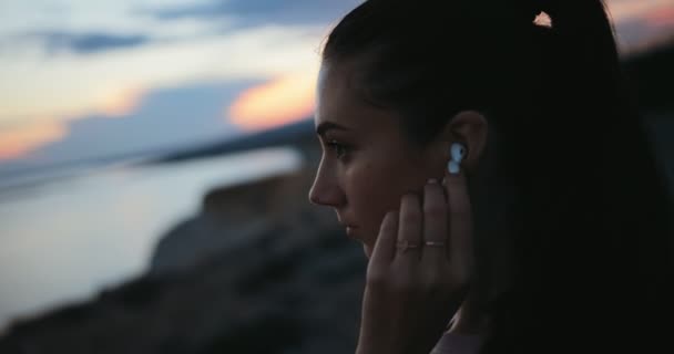 Женщина слушает музыку после тренировки у моря — стоковое видео