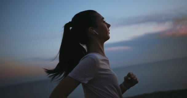 Mulher ativa correndo no penhasco do mar e ouvindo música — Vídeo de Stock