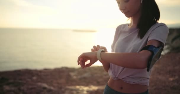 Νεαρή γυναίκα δρομέας που χρησιμοποιεί smartwatch κατά τη διάρκεια της αθλητικής κατάρτισης σε εξωτερικούς χώρους — Αρχείο Βίντεο