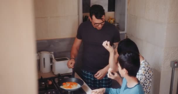 Otec a synové vaří vejce k snídani ráno