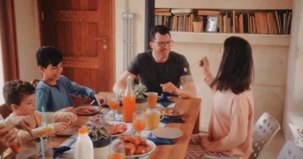 Feliz esposa alimentación marido panqueques durante el desayuno con la familia — Vídeos de Stock