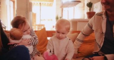 İki kızı olan bir aile birlikte kanepede dinleniyor.