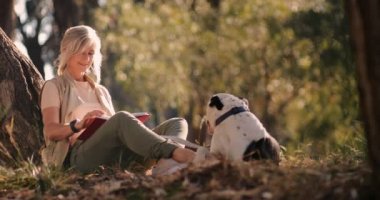 Parkta köpek okuma kitabı olan mutlu son sınıf kadını.