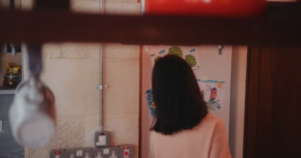 Joven madre abriendo la puerta del refrigerador y poniendo leche dentro — Vídeos de Stock