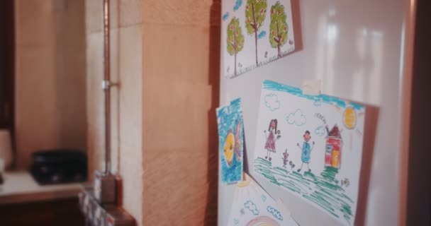 Junge Mutter öffnet Kühlschranktür mit Kinderzeichnungen in Küche — Stockvideo