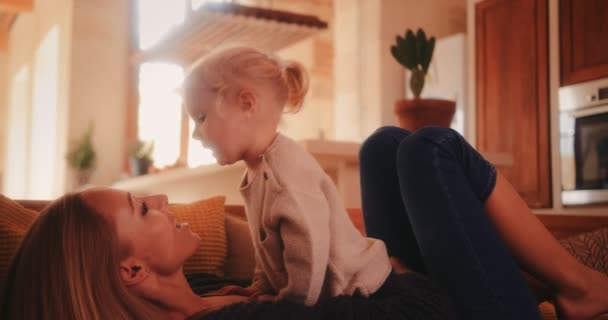 Mãe feliz e filha beijando e relaxando no sofá — Vídeo de Stock