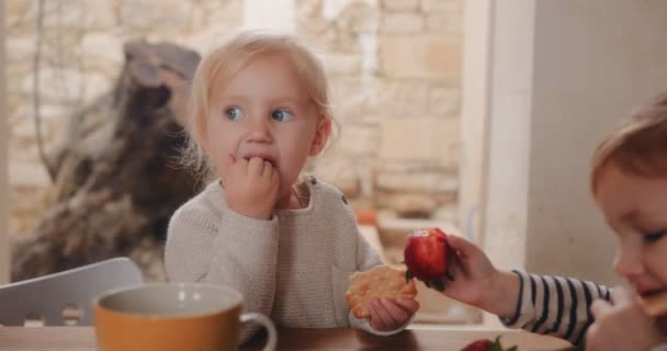 Děti si užívají zdravou svačinu s jahodami v kuchyni rodinného domu
