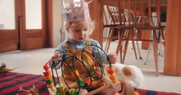 Petite fille jouant avec jouet éducatif en bois sur le sol de la cuisine — Video