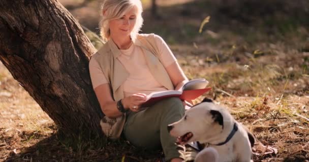 Femme mûre avec chien assis sous l'arbre et le livre de lecture — Video