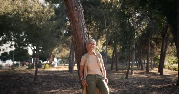 Mujer madura de moda relajándose en el bosque en un día soleado — Vídeo de stock