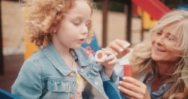 Allegro nonna e nipote divertirsi soffiando bolle al parco giochi — Video Stock