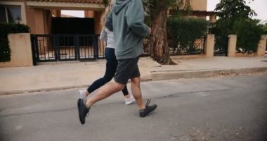 Üst düzey çok ırklı çift birlikte egzersiz yapıyor ve banliyö sokaklarında koşuyor.