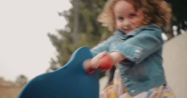 Adorable niña con el pelo rubio jugando en el parque de juegos — Vídeos de Stock