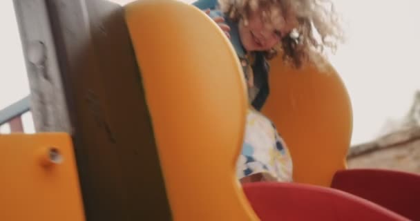 Симпатична маленька дівчинка з світлим волоссям ковзає вниз дитячий майданчик слайд — стокове відео