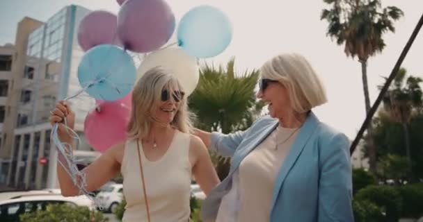 Alegres mujeres maduras celebrando con globos en la ciudad — Vídeos de Stock