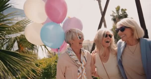 Mujeres maduras amigas divirtiéndose en la ciudad con globos — Vídeo de stock