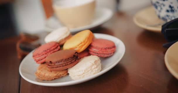 Bunte Macarons serviert auf Holztisch mit Kaffee und Tee — Stockvideo