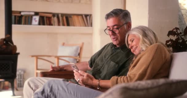 Αγαπώντας το ζευγάρι ηλικιωμένων χρησιμοποιώντας smartphone και γελώντας μαζί στο σπίτι — Αρχείο Βίντεο