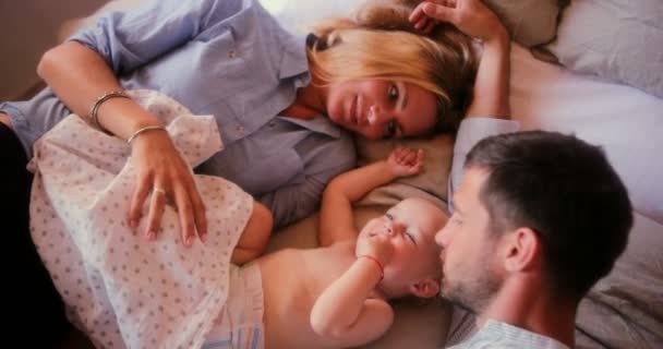 Familia feliz con la niña divirtiéndose en la cama — Vídeo de stock