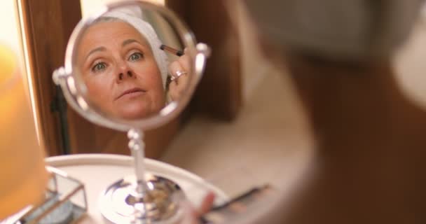 Spiegel reflectie van mooie volwassen vrouw aanbrengen make-up thuis — Stockvideo