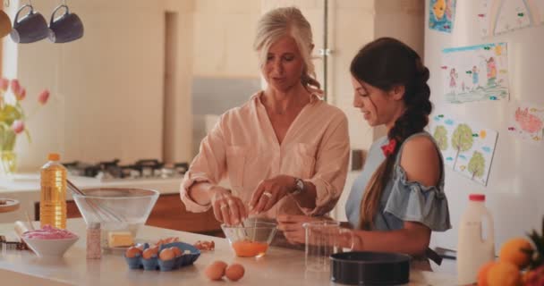 Счастливая бабушка и внучка пекут дома на кухне — стоковое видео