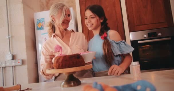 Grootmoeder en kleindochter hebben plezier glazuur zelfgemaakte taart in de keuken — Stockvideo