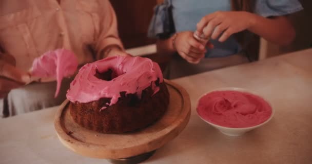 Abuela y nieta decoración de la torta con hielo y espolvoreos — Vídeos de Stock